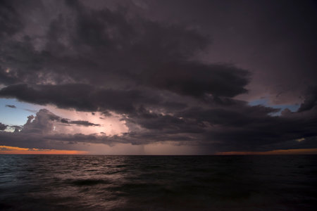 Thunderstorm clouds over rough ocean waters. Evening sea waves crushing on sandy beach. Beautiful...