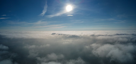 Aerial view from high altitude of earth covered with white puffy cumulus clouds on sunny day