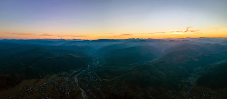 Aerial view of dark mountain hills at sunset. Hazy peaks and misty valleys in evening