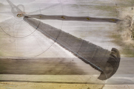 Agricultural irrigation sprinkler watering dry soil on farm field for crops growing during period of droughtの写真素材