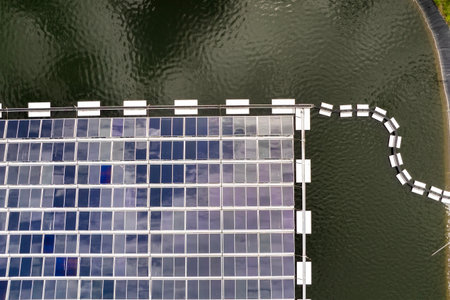 Floating solar energy plant with rows of photovoltaic panels mounted on water, producing renewable electricity without air pollution. Concept of eco-friendly power generation on industrial reservoirs.の写真素材