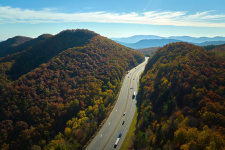 I-40 freeway road leading to Asheville in North Carolina over Appalachian mountain pass with yellow fall forest and fast moving trucks and cars. Concept of high speed interstate transportation.の写真素材