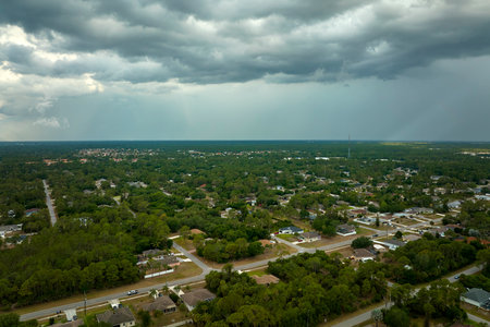 Landscape of dark ominous clouds forming on stormy sky before heavy thunderstorm over rural town areaの写真素材