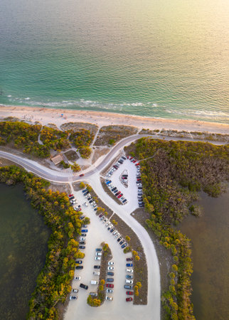 Parking lot for tourists cars in front of ocean beach with soft white sand in Florida. Popular vacation spot at sunsetの写真素材