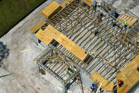 Professional builders working on roof construction of unfinished suburban home with wooden frame structure in Florida rural area. Concept of housing development in Americaの写真素材