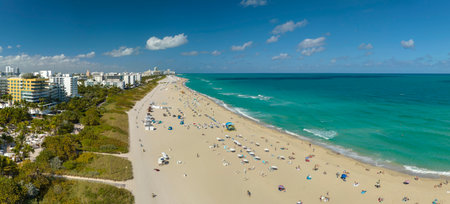 Tourism infrastructure in southern USA. South Beach sandy surface with tourists relaxing on hot Florida sun. Miami Beach city with high luxury hotels and condosの写真素材