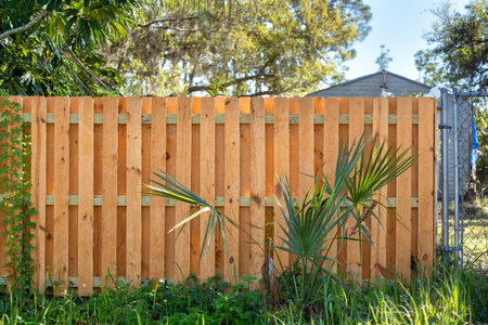 Wooden picket fence on green lawn surrounding property grounds for backyard protection and privacyの写真素材
