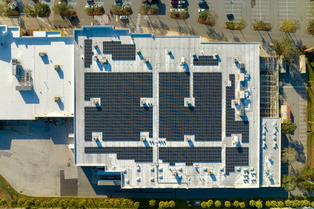 Aerial view of solar power plant with blue photovoltaic panels mounted on industrial building roof for producing green ecological electricity. Production of sustainable energy conceptの写真素材