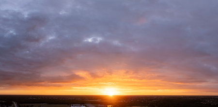 Beautiful sunset sky over dark landscape. Bright colorful orange and yellow clouds on horizonの写真素材
