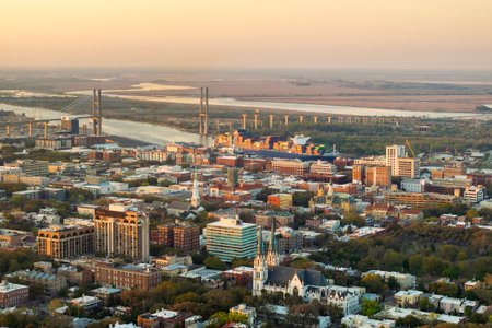 Cargo container ship departing from port terminal in Savannah, Georgia. American architecture with illuminated streets and historical buildingsの写真素材