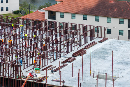 Construction site with hardhat workers assembling metal frame walls. Aerial view of large development area of commercial structure. Real estate market in the USAの写真素材