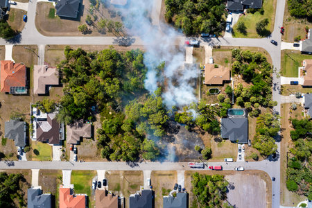 Firefighters battle a fast moving wildfire in Florida forest near suburban homes with fire trucks stationed close on residential streetの写真素材