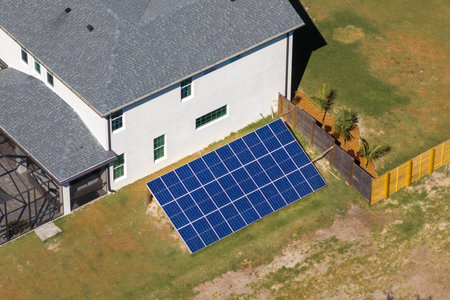 Private home with solar photovoltaic panels mounted on stand-alone frame on backyard ground for generating of clean ecological electric energy in suburban rural town area. Concept of autonomous houseの写真素材