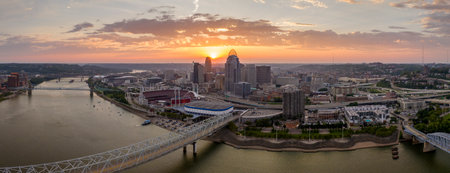 Sunset urban landscape of downtown district of Cincinnati city in Ohio, USA. Skyline with bridge traffic and brightly illuminated high skyscraper buildings in modern American megapolisの写真素材