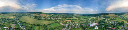 Aerial landscape view of green cultivated agricultural fields with growing crops and distant village...