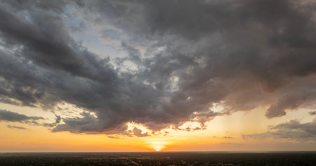 Colorful sunset sky with setting sun behind vivid orange and yellow clouds