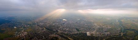 Aerial view from high altitude of distant city covered with puffy cumulus clouds flying by before...