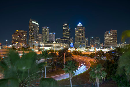 American city skyline of Tampa in Florida. Brightly illuminated commercial buildings and high speed highway road. Night urban landscape of downtown district in USA.の写真素材