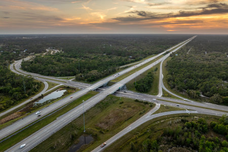 Elevated view of freeway exit junction over road lanes with fast moving traffic cars and trucks at sunrise. Interstate transportation infrastructure in USAの写真素材