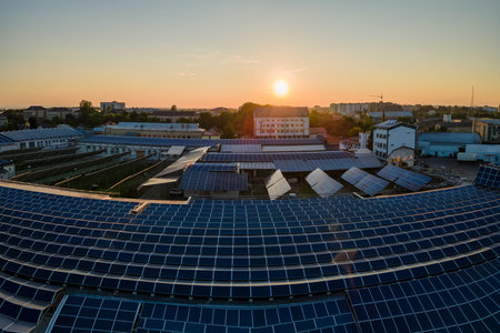 Aerial view of blue photovoltaic solar panels mounted on industrial building roof for producing...