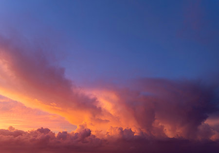 Bright sunset with setting sun behind vivid orange and yellow clouds