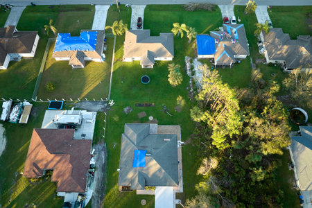 Hurricane Ian damaged house rooftops covered with protective plastic tarp against rain water leaking...
