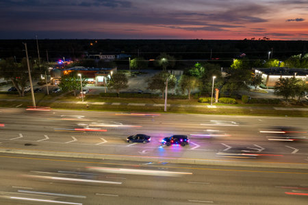 Police vehicle with emergency lights stops a driver for speeding on city road at night in the United...