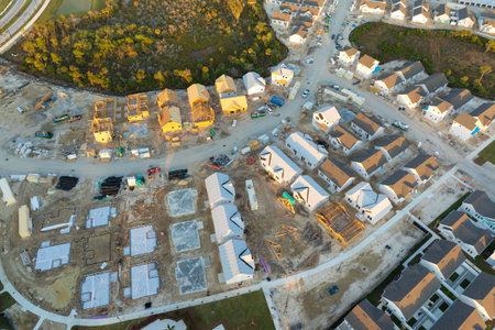 Aerial view of unfinished wooden frames of affordable houses under construction. Development of...