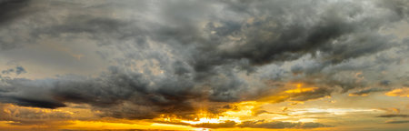 Dramatic sunset sky covered with colorful yellow clouds. Panoramic skyscape