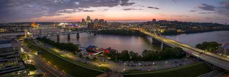 Night urban landscape of downtown district of Cincinnati city in Ohio, USA. Skyline with bridge traffic and brightly illuminated high skyscraper buildings in modern American megapolisの写真素材