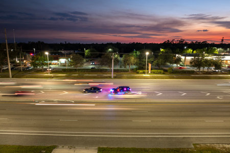 City street at night with police conducting a stop on a speeding car. Flashing red and blue lights...