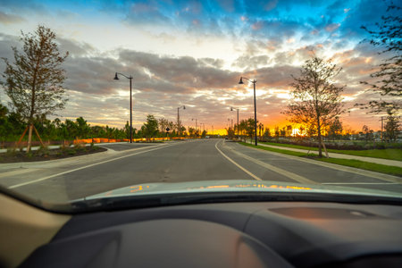POV driving scene through Florida town during golden hour, dashboard and windshield visible, cars...