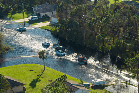 Hurricane flooded street with moving cars and surrounded with water houses in Florida residential...