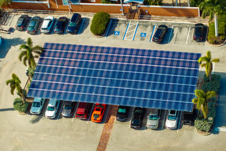 Solar panels installed as shade roof over parking area with parked cars for effective generation of...