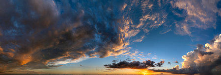 Colorful sunset sky with setting sun behind vivid orange and yellow clouds