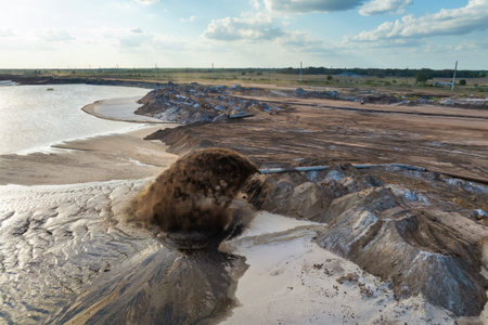 Industrial pipe spraying mixture of water and sediment at mining area, part of phosphate extraction...