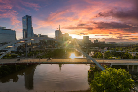 Korean Veterans Memorial Bridge in Nashville city, Tennessee, USA. Highway traffic driving cars in downtown district. American city skyline with brightly illuminated buildings at sunset.