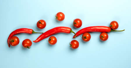 Red chili peppers and tomatoes isolated on blue background.の写真素材