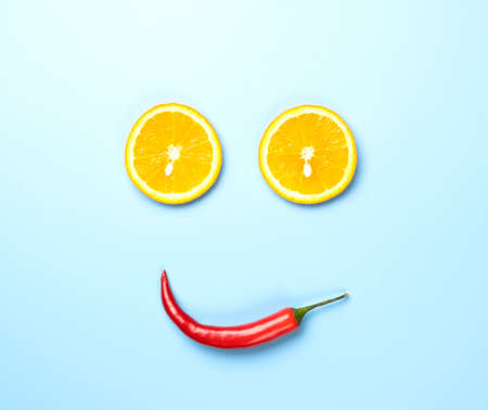 Red chili peppers and slices of lemon in smile form isolated on blue background.の写真素材