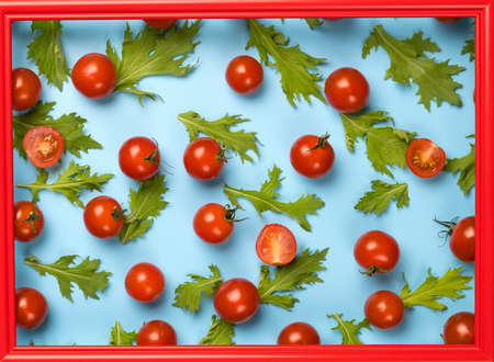 Red cherry tomatoes and green rucola salad leaves on blue background.の写真素材