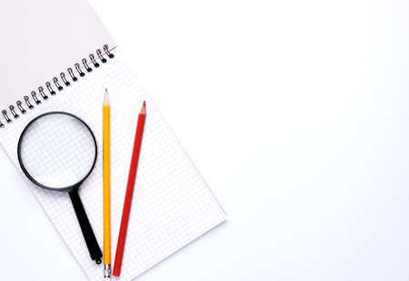 Blank white open notepad and magnifying glass on copy space background.