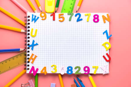 Many different school supplies and empty notepad white sheet of paper on pink copy space background....