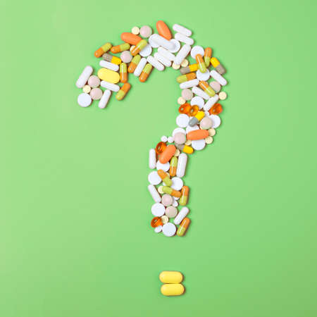 Close up of many different pills in question mark sign form on green background.の写真素材