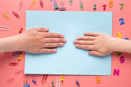 Human hands on blue sheet of paper with pink background.の写真素材
