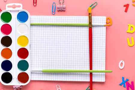 Bright watercolor paints and brushes on white notepad sheet of paper copy space background.の写真素材