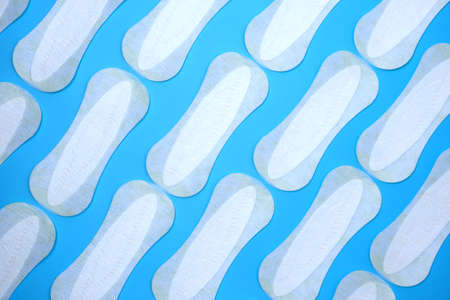 Flat lay pattern of clean unused sanitary woman pads on blue background.の写真素材