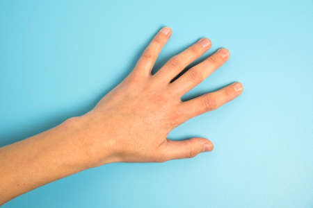 Close up of man's hand isolated on blue backgroundの写真素材