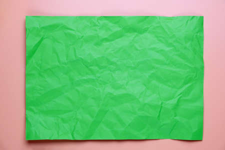 Close up of green crumpled empty sheet of paper on pink background.の写真素材