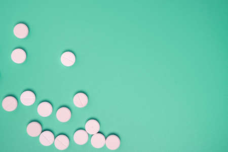 Close up of many white pills on green background.の写真素材