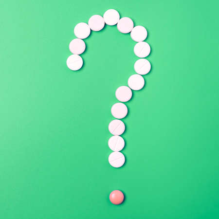 Close up of many different pills in question mark sign form on green background.の写真素材